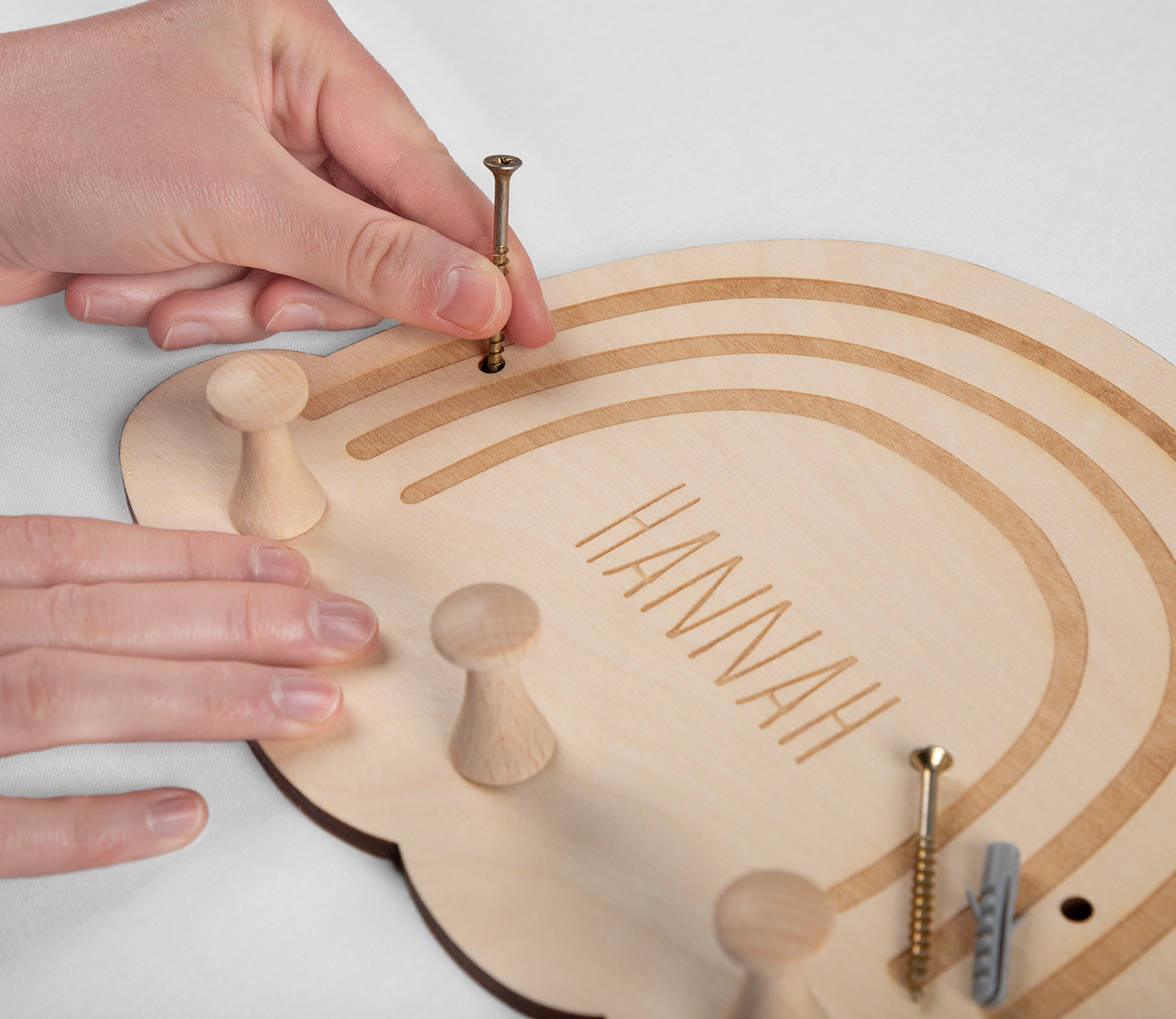 Personalisierte Kindergarderobe aus Holz, Ornamente sowie auch der Name sind mit Laser ausgefräst worden. Die Garderobe wird gerade befestigt.