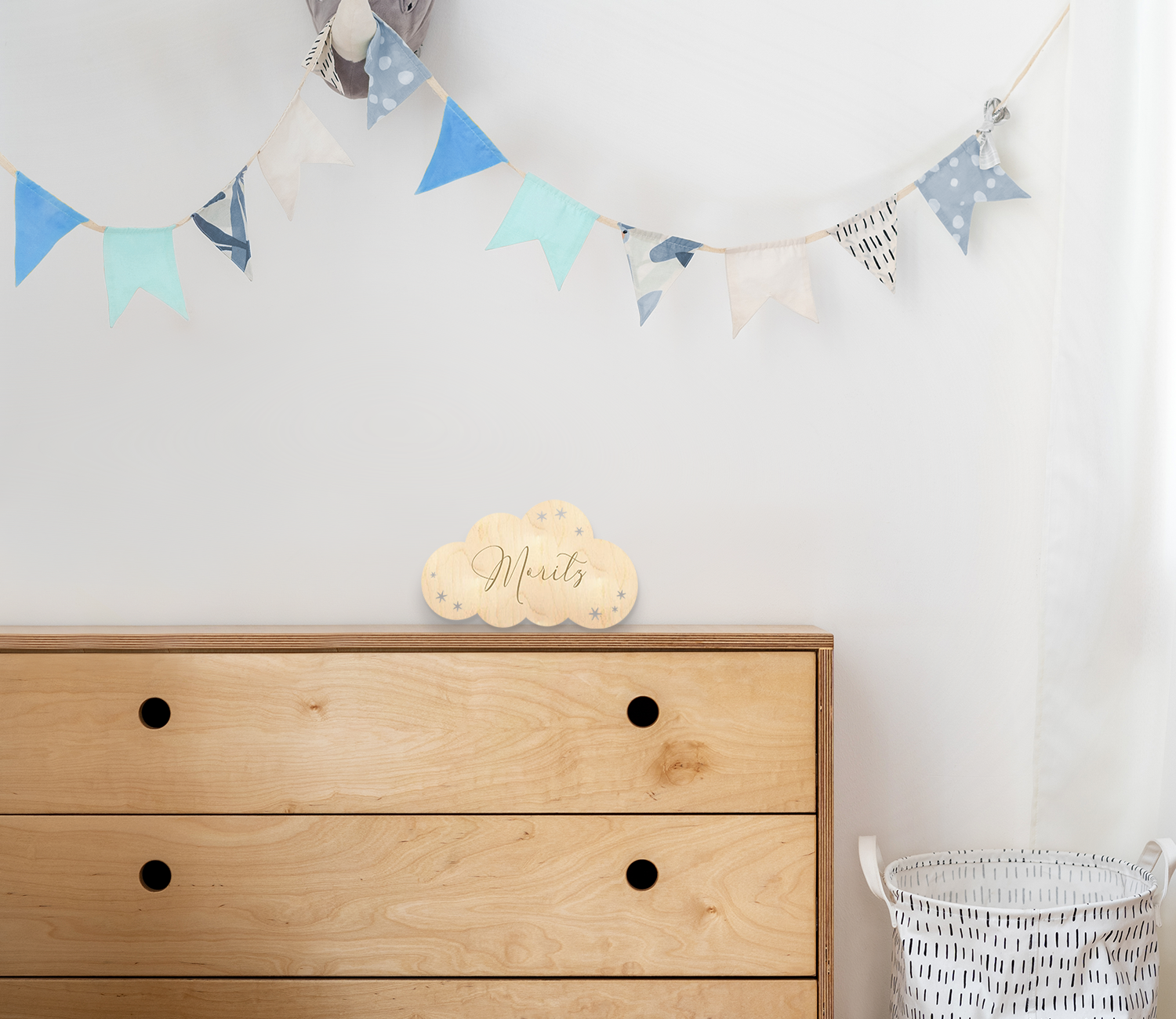 Wandschild in Wolkenform aus Holz mit graviertem Namen und ausgelaserten Sternen aufgestellt auf Kommode in Kinderzimmer.