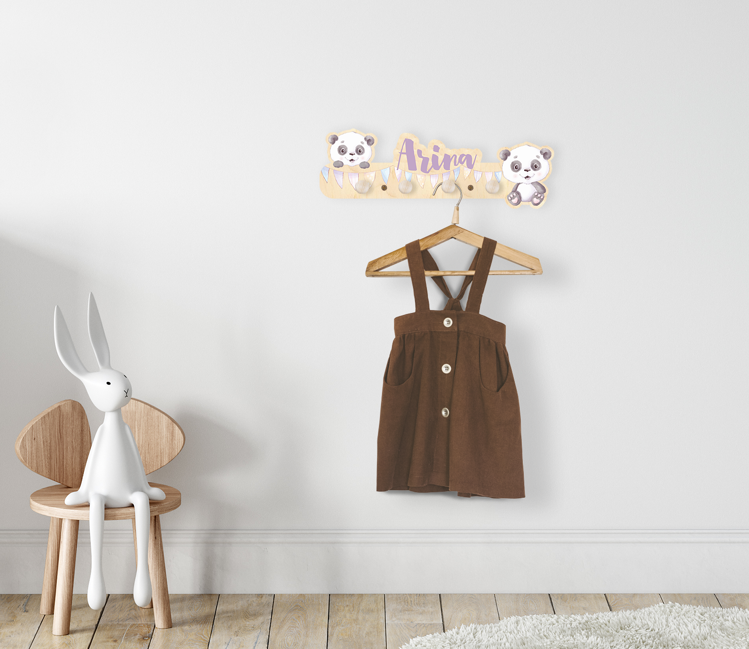 Kindergarderobe mit Panadabären und Namen aus Holz montiert an einer Kinderzimmerwand. An der Garderobe hängt ein Kleiderhaken mit einem Kleidungsstück.
